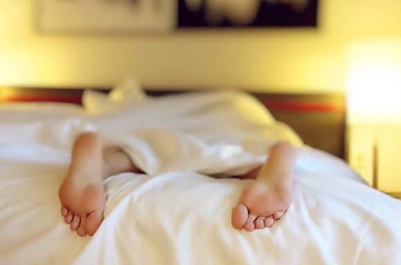 femme dormant dans un lit les pieds à l'air